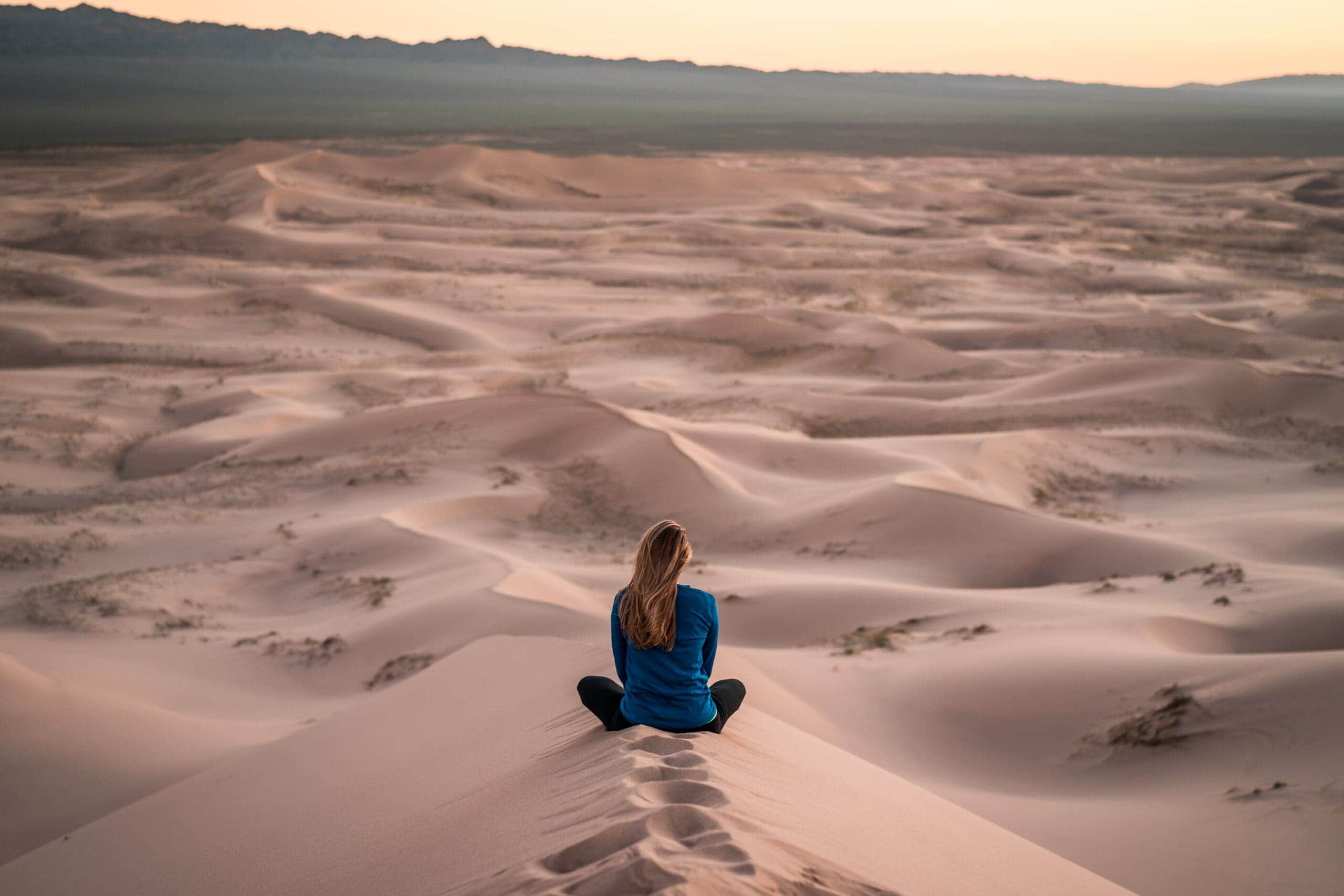 A person sitting cross-legged with eyes closed, meditating in a peaceful environment.