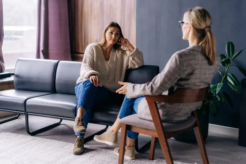 A person meeting with a psychedelic therapist in a warm, plant-filled therapeutic space